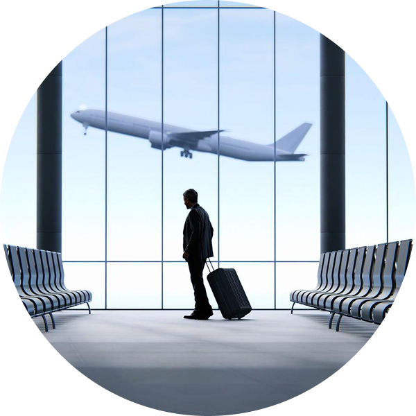 Silhouette of a traveler with a rolling suitcase standing between airport benches, watching an airplane fly past the terminal window